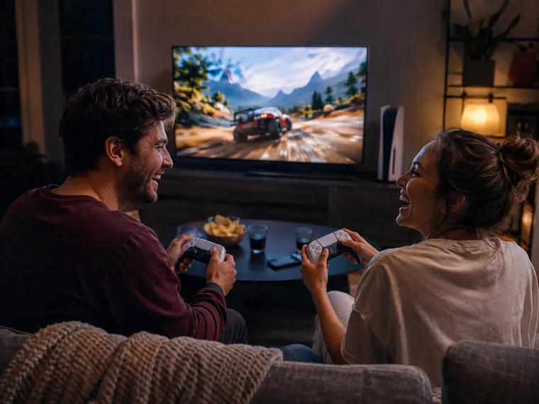 Двое играют на PlayStation 5 вечером